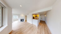 Located at 1011 Pike St in the heart of Seattle, WA, this one-bedroom, one-bathroom residence offers a well-designed single-floor layout with thoughtful finishes throughout. The open living area is bathed in natural light from a generous bank of large windows that frame striking views of Seattle's urban skyline and surrounding cityscape, creating a bright and airy atmosphere. Light-toned hardwood flooring runs throughout the main living spaces, lending warmth and continuity to the interior. A fireplace serves as a focal point in the living area, adding a classic touch to the modern aesthetic. The kitchen is positioned in a semi-open layout behind a peninsula featuring granite countertops and a sink, complemented by warm wood cabinetry, stainless steel appliances, and recessed lighting overhead. The bedroom is a calm, private retreat with its own window for natural light and the same clean hardwood flooring. The bathroom is finished with tile flooring, a granite-topped vanity with white cabinetry, a lighted mirror, and a full soaking tub with shower. A hallway connects the spaces efficiently, contributing to a functional and cohesive floor plan ideal for urban living in one of Seattle's most vibrant neighborhoods.