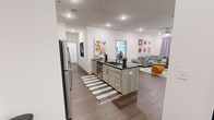 Located at 1300 5th Avenue South in Birmingham, AL, this well-appointed single-floor unit offers four bedrooms and four bathrooms across a generously sized layout. The open-concept kitchen and living area serves as the heart of the home, featuring a large center island with dark granite countertops, light wood cabinetry, stainless steel appliances including a full-size refrigerator and microwave, and bar seating for casual dining. The kitchen flows seamlessly into the living room, which is brightened by recessed lighting, a ceiling fan, and a window dressed with soft curtains. Rich wood-tone flooring runs throughout the common areas, adding warmth and continuity to the space. Each of the four bedrooms offers a clean, minimalist atmosphere with white walls and hardwood-style flooring, while three dedicated closets provide wire-rack shelving systems for organized storage. The four bathrooms are finished with tub-shower combinations and clean, neutral fixtures. Hallways connect each private bedroom suite efficiently throughout the floor plan. The overall aesthetic is modern and vibrant, accented by colorful wall art visible throughout the shared spaces, creating a lively yet functional environment suited for shared or family living.