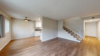 This two-story home offers four bedrooms and two bathrooms across a well-distributed layout. The main floor features a welcoming living area with wood-look vinyl flooring, neutral-toned walls, and multiple windows that invite abundant natural light and outdoor views. A ceiling fan adds comfort to the open living space, which flows conveniently toward a galley-style kitchen. The kitchen is outfitted with white shaker cabinetry, dark countertops, a stainless steel sink, and stainless steel appliances including a refrigerator and range, all beneath a skylight that brightens the workspace. A carpeted staircase with a light wood railing connects the two floors. The upper level hosts the bedrooms, including a generously sized primary bedroom, all featuring plush carpeting and textured ceilings. The bedrooms are served by two full bathrooms, each featuring a tub-shower combination with white tile surround, updated white vanity cabinetry with dark countertops, and wood-look flooring. Hallways on both floors provide easy circulation throughout the home. Textured ceilings are consistent throughout the space, contributing to the home's classic residential character. Overall, the home presents a clean, functional design with updated finishes throughout.