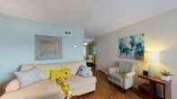 This two-floor residence offers a well-organized layout with distinct living spaces designed for comfort and functionality. The living room serves as the heart of the home, featuring warm hardwood flooring, a textured ceiling, and a calming color palette highlighted by a soft blue accent wall. The space is open and inviting, flowing naturally into a dedicated dining area adorned with an olive green accent wall, hardwood floors, and a sliding glass door that fills the room with natural light. The galley-style kitchen is efficiently designed with white cabinetry, dark countertops, black appliances, and a window above the sink that brings in additional light. The bedrooms are carpeted for comfort and each includes a ceiling fan with light fixture, neutral wall tones, and windows dressed with sheer white curtains. The bathrooms are clean and functional, with one featuring hardwood flooring, a vanity with dark countertops, and colorful wall art, while another offers a straightforward vanity with a mirror and stone-finish countertop. Throughout the residence, consistent warm tones, tasteful artwork, and thoughtful accents create a cohesive and welcoming ambiance across both floors.