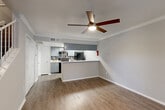 Located at 10615 Meadowglen Ln in Houston, TX, this two-story residence is thoughtfully laid out across two floors. The main level opens with an entrance that flows into a combined living and dining area, finished with warm wood-look flooring and crown molding throughout. A ceiling fan adds comfort to the space, which is bathed in natural light from multiple windows offering views of the surrounding greenery. The kitchen is a functional highlight, featuring gray cabinetry, a mosaic tile backsplash, white countertops, black appliances, and a peninsula breakfast bar that connects seamlessly to the living area. A pantry and additional closet storage add practical convenience on this level. Soaring ceilings in the living area lend an airy, open feel, accentuated by high windows that draw in abundant natural light. The upper floor hosts a loft space, two closets — including a walk-in closet with built-in hanging rods — and two full bathrooms, each with wood-look flooring and a tub-shower combination. A hallway and two staircases ensure smooth circulation between floors. The clean, neutral color palette and consistent flooring throughout create a cohesive and modern ambiance.