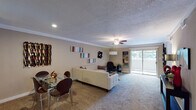 This single-floor residence offers a thoughtfully arranged layout that balances comfort and functionality across multiple living areas. The open-concept living and dining space serves as the heart of the home, featuring wall-to-wall carpet, crown molding, and a textured ceiling with a ceiling fan overhead. Recessed lighting complements the natural light streaming through a sliding glass door that opens to an outdoor area, enhancing the room's bright and welcoming ambiance. A glass-top dining table sits comfortably alongside the living area, creating a seamless flow between the two spaces.

The galley-style kitchen is efficiently designed with dark espresso cabinetry, dark granite countertops, and a mosaic tile backsplash. Stainless steel appliances, including a refrigerator, electric range, dishwasher, and built-in microwave, line both sides of the kitchen, while tile flooring adds a clean, practical finish.

The primary bedroom is generously proportioned, featuring plush carpet, crown molding, ceiling fan, and multiple windows that bring in ample natural light. A dark-toned open shelving unit serves as a stylish room divider. An additional room functions well as a home office or guest space, also carpeted and naturally lit. The bathroom features full stone-look tile walls, a soaking tub with glass enclosure, and coordinating tile flooring.
