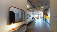 Located on W Hope Street in Alameda, California, this single-floor industrial loft blends raw architectural character with modern comfort. The open-plan layout is anchored by soaring exposed concrete ceilings with visible structural beams and track lighting running overhead, while polished concrete floors extend seamlessly throughout the entire space.

The main living area is generously proportioned, featuring a boldly painted dark accent wall that anchors a comfortable seating arrangement centered around a flat-screen TV. Large industrial-style windows along the far wall flood the space with natural light and lend an airy, expansive feel. A striking original concrete column adds to the authentic loft aesthetic.

The dining area sits centrally within the open floor plan, offering a natural transition between the sleeping and living zones. The kitchen is well-appointed with warm wood cabinetry, under-cabinet lighting, subway tile backsplash, stainless steel appliances, and in-unit washer and dryer conveniently positioned nearby.

The sleeping area is integrated within the open layout, defined by a partial dividing wall that provides a sense of privacy without disrupting the loft's open character. The bathroom features classic white subway tile surrounding the tub-shower combination, decorative patterned floor tile, and clean, minimalist fixtures. This space is a compelling example of adaptive industrial design in the heart of the East Bay.