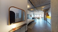 Located on W Hope Street in Alameda, California, this single-floor industrial loft blends raw architectural character with modern comfort. The open-plan layout is anchored by soaring exposed concrete ceilings with visible structural beams and track lighting running overhead, while polished concrete floors extend seamlessly throughout the entire space.

The main living area is generously proportioned, featuring a boldly painted dark accent wall that anchors a comfortable seating arrangement centered around a flat-screen TV. Large industrial-style windows along the far wall flood the space with natural light and lend an airy, expansive feel. A striking original concrete column adds to the authentic loft aesthetic.

The dining area sits centrally within the open floor plan, offering a natural transition between the sleeping and living zones. The kitchen is well-appointed with warm wood cabinetry, under-cabinet lighting, subway tile backsplash, stainless steel appliances, and in-unit washer and dryer conveniently positioned nearby.

The sleeping area is integrated within the open layout, defined by a partial dividing wall that provides a sense of privacy without disrupting the loft's open character. The bathroom features classic white subway tile surrounding the tub-shower combination, decorative patterned floor tile, and clean, minimalist fixtures. This space is a compelling example of adaptive industrial design in the heart of the East Bay.