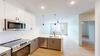 This well-appointed one-bedroom, one-bathroom residence at 212 Durham Avenue in Metuchen, NJ offers a thoughtfully designed open-concept layout with clean, modern finishes throughout. Light hardwood flooring flows seamlessly across the entire space, creating a warm and cohesive aesthetic.

The combined kitchen and living area serves as the heart of the home. The kitchen is outfitted with stainless steel appliances, including a French door refrigerator, electric range, and over-the-range microwave. Two-toned cabinetry — white uppers and gray lowers — pairs with white quartz countertops and a large peninsula featuring a undermount sink and stylish pendant lighting, making it equally functional and visually striking.

The bedroom is a comfortable, well-lit retreat with a ceiling fan, natural light from a window with exterior views, and direct access to a private balcony. A dedicated closet provides practical storage. Additional in-unit laundry is conveniently located within the space.

The bathroom features a gray double-vanity with a white quartz countertop, a large mirror, light wood-look tile flooring, and matte black fixtures and hardware throughout, lending a refined, contemporary touch.

Neutral walls, recessed lighting, and a clean design palette give the entire residence a bright, modern ambiance ideal for comfortable everyday living.
