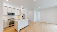 Located on Santa Monica Boulevard in the heart of West Los Angeles, this thoughtfully designed 2-bedroom, 1-bathroom residence showcases a clean, modern aesthetic throughout. Light-toned hardwood flooring flows seamlessly through the open-concept living and kitchen area, anchored by a striking white kitchen island with quartz countertops. The kitchen is outfitted with stainless steel appliances, a gas range, a full-size French door refrigerator, and sleek white flat-front cabinetry complemented by a classic tile backsplash. Recessed lighting illuminates the entire space. A bright hallway with recessed lighting connects the main living area to the private quarters. The spacious primary bedroom features large sliding glass doors that open to views of the surrounding building courtyard, filling the room with natural light. Both bedrooms are finished with plush neutral carpeting and crisp white walls. A dedicated closet provides additional storage. The bathroom offers a frameless glass walk-in shower with marble-style tile surround, a floating vanity with quartz countertop, and a clean, all-white finish. Two hallways provide an efficient layout with easy access to all rooms, rounding out this polished and well-appointed residence.