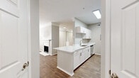 Located at 195 E Round Grove Rd in Lewisville, TX, this well-appointed one-bedroom, one-bathroom residence offers a thoughtfully designed single-floor layout. The open-concept kitchen and living area serves as the heart of the home, anchored by a classic white-mantled fireplace and warm wood-look flooring that flows throughout. A ceiling fan overhead enhances comfort, while natural light fills the space through large windows with blinds. The kitchen is efficiently designed with white shaker cabinetry, white quartz countertops, a subway tile backsplash, stainless steel appliances including a refrigerator, range, microwave, and dishwasher, plus a peninsula that provides additional workspace and casual dining potential. The bedroom is carpeted for comfort and features its own ceiling fan, a sunlit window, and access to a generously sized walk-in closet outfitted with wire shelving on three walls. The bathroom offers a clean, modern aesthetic with white cabinetry, a quartz vanity, a full tub-shower combination, and wood-look flooring. A dedicated laundry room with a full-size washer and dryer adds everyday convenience. Crown molding and neutral tones throughout lend a cohesive, polished finish to the entire space.