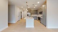 Located at 55 Gardner Dr on beautiful Hilton Head Island, SC, this thoughtfully designed single-story home offers a clean, contemporary aesthetic throughout. The open-concept kitchen serves as the heart of the home, featuring a large center island with a built-in sink, white quartz countertops, gray shaker-style cabinetry, a subway tile backsplash, and stainless steel appliances. Elegant pendant lighting illuminates the island, while recessed lighting brightens the entire space. Light-toned hardwood-style flooring flows through the main living areas, enhancing the home's airy, modern feel. Natural light pours in through multiple windows, offering views of the surrounding greenery. The bedrooms are carpeted for comfort and include generous windows that frame lush outdoor scenery, with ceiling fans providing additional comfort. A spacious walk-in closet with wire shelving provides ample storage. The primary bathroom is generously proportioned, featuring a dual-sink vanity with quartz countertops, a glass-enclosed walk-in shower with large-format tile, and light tile flooring. A secondary bathroom offers a tiled tub-shower combination with classic subway tile surround. Throughout the home, a neutral color palette and quality finishes create a cohesive, move-in-ready environment.