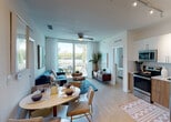 Located at 5375 NW Seventh St in Miami, FL, this single-floor residence offers a thoughtfully designed open-concept layout that seamlessly connects the kitchen, dining, and living areas. Light wood-look flooring runs throughout, complementing the bright, airy atmosphere created by large sliding glass doors that flood the space with natural light and lead to a private balcony with outdoor seating and lush tropical views.

The kitchen is outfitted with stainless steel appliances, including a range, microwave, and refrigerator, paired with two-tone cabinetry featuring crisp white upper cabinets and warm wood lower cabinets, all anchored by a clean tile backsplash. Track lighting and generous counter space make this an efficient and stylish cooking area.

The living room centers around a ceiling fan, a cozy seating arrangement, and direct balcony access, creating a relaxed coastal atmosphere. The dining area comfortably accommodates a round table and chairs just steps from the kitchen.

The bedroom is a serene retreat with its own ceiling fan, large windows draped in sheer curtains, and an abundance of natural light. A closet and dedicated storage provide practical functionality.

The bathroom features wood-look tile walls surrounding a soaking tub and shower combination, complemented by warm-toned floor tiles, offering a spa-like feel. The overall design reflects a clean, modern coastal sensibility well-suited to Miami living.