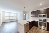 This thoughtfully designed 2-bedroom, 2-bathroom residence at 50 Woodview Way in Franklin, MA offers a comfortable and modern living experience across a single floor. The kitchen serves as the centerpiece of the home, boasting rich dark cabinetry, stainless steel appliances including a refrigerator, microwave, and range, a white quartz peninsula with an undermount sink, subway tile backsplash, and warm wood-look flooring. Pendant lighting above the peninsula adds a polished finishing touch. Both bedrooms are carpeted and bathed in natural light through multiple windows with blinds, offering a calm and restful atmosphere. The spacious primary bedroom includes generous closet space outfitted with wire shelving systems, providing ample organization. The two bathrooms each feature a tub-shower combination with classic white subway tile surrounds, offering a clean and timeless aesthetic. A well-lit hallway connects the living spaces, finished with neutral tones and panel-style doors throughout. With two dedicated closets and a practical layout, this residence balances everyday functionality with a clean, contemporary design sensibility well-suited to modern living in Franklin, MA.