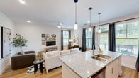 Located in Huntersville, NC, this single-floor, 2-bedroom, 2-bathroom home offers a thoughtfully designed layout with modern finishes throughout. Warm hardwood-style flooring flows seamlessly across every room, complemented by a clean, neutral color palette that creates a bright and welcoming atmosphere.

The open-concept kitchen and living area forms the heart of the home. The kitchen is equipped with stainless steel appliances, crisp white cabinetry, granite countertops, and a peninsula with a built-in sink — ideal for both cooking and entertaining. Pendant lighting and recessed fixtures add a polished touch, while a window frames lush outdoor greenery.

The living room is a comfortable, well-lit space featuring recessed lighting and a ceiling fan. Its open flow connects effortlessly to the kitchen, making it a versatile area for daily living.

The generously sized primary bedroom features large windows that invite natural light and offer views of the surrounding landscape, along with a ceiling fan for added comfort. The en-suite bathroom includes a granite-topped vanity and a glass-enclosed shower, with built-in open shelving providing ample storage.

The second bedroom includes a double-door closet and easy hallway access to the second full bathroom, which also features a granite vanity. A private patio overlooks a peaceful green space lined with tall trees, offering a tranquil outdoor retreat.