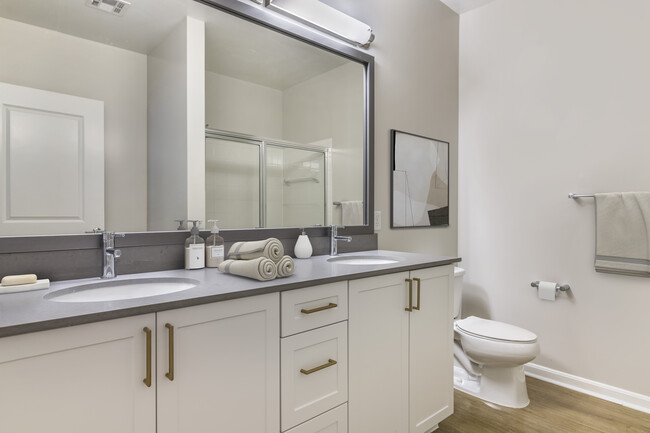 Renovated Package II bath with grey quartz countertops, white cabinetry, and hard surface flooring - Avalon at Assembly Row