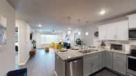 Located in Springfield, MO, this single-floor residence offers a thoughtfully designed open-concept layout with contemporary finishes throughout. The kitchen is a standout feature, equipped with stainless steel appliances, granite countertops, a dual-tone cabinetry scheme of white upper and gray lower cabinets, a tile backsplash, and a large island with pendant lighting and bar seating — ideal for both cooking and entertaining. The kitchen flows seamlessly into the living area, which is bright and welcoming, featuring wood-style flooring, recessed lighting, a ceiling fan, and a large window that fills the space with natural light and outdoor views. Two well-appointed bedrooms offer carpeted flooring, generous closet space, ceiling fans, and windows overlooking the surroundings. The primary bathroom includes a double-sink granite vanity with gray cabinetry, a built-in makeup area, and wood-style flooring. The secondary bathroom mirrors the upscale finishes with a granite vanity, oversized mirror, and a shower-tub combination. Throughout the residence, a cohesive neutral color palette with gray tones and modern hardware creates a clean, sophisticated ambiance suited for contemporary living.