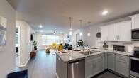 Located in Springfield, MO, this single-floor residence offers a thoughtfully designed open-concept layout with contemporary finishes throughout. The kitchen is a standout feature, equipped with stainless steel appliances, granite countertops, a dual-tone cabinetry scheme of white upper and gray lower cabinets, a tile backsplash, and a large island with pendant lighting and bar seating — ideal for both cooking and entertaining. The kitchen flows seamlessly into the living area, which is bright and welcoming, featuring wood-style flooring, recessed lighting, a ceiling fan, and a large window that fills the space with natural light and outdoor views. Two well-appointed bedrooms offer carpeted flooring, generous closet space, ceiling fans, and windows overlooking the surroundings. The primary bathroom includes a double-sink granite vanity with gray cabinetry, a built-in makeup area, and wood-style flooring. The secondary bathroom mirrors the upscale finishes with a granite vanity, oversized mirror, and a shower-tub combination. Throughout the residence, a cohesive neutral color palette with gray tones and modern hardware creates a clean, sophisticated ambiance suited for contemporary living.