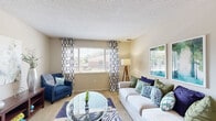 This single-floor residence offers a thoughtfully designed layout across two bedrooms and two bathrooms. The living room is a bright and welcoming space, featuring large windows dressed with patterned curtains that allow generous natural light to fill the carpeted room. Neutral-toned walls and a textured ceiling complement the comfortable, open atmosphere. Adjacent to the living area, the dining room provides a dedicated space for meals, highlighted by a sliding glass door that opens directly onto a private balcony overlooking lush greenery — a standout feature that seamlessly connects indoor and outdoor living. The galley-style kitchen is efficiently organized with warm wood cabinetry, white countertops, tile flooring, and full appliances including a dishwasher and refrigerator. The primary bedroom is a spacious retreat with wide windows, soft carpet, and direct access to both a closet and a private bathroom. The second bedroom also features large windows and plush carpeting, offering a bright and versatile space. Both bathrooms are finished with tile flooring, wood vanities, and well-lit mirrors. A hallway and dedicated closet provide additional storage and circulation throughout the home. Overall, the residence presents a clean, functional, and inviting environment.