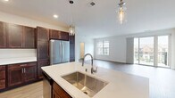 Located at 6330 W Spur Rd in Mequon, Wisconsin, this well-appointed 2-bedroom, 2-bathroom single-floor unit offers a thoughtfully designed layout with modern finishes throughout. The open-concept kitchen and living area serves as the heart of the home, anchored by a large center island with a white quartz countertop, an undermount stainless steel sink, and elegant pendant lighting. Rich dark-wood cabinetry lines the kitchen walls, complemented by a full suite of stainless steel appliances including a refrigerator, range, and microwave. Light hardwood-style flooring flows seamlessly through the main living area, enhancing the bright, airy atmosphere. The spacious living room features sliding glass doors that open to a private balcony, bringing in generous natural light and views of the surrounding neighborhood. Both bedrooms are carpeted and well-lit by large windows with exterior views, offering a calm and comfortable retreat. The primary bedroom is generously sized with ample closet space. The bathrooms are finished with dark wood vanities, white quartz countertops, large mirrors, and the primary bath includes a walk-in glass-door shower with white tile surround. A utility room and three closets round out the functional floor plan, providing practical storage throughout.