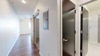 Located at 820 N Sherman St in Denver's Capitol Hill neighborhood, this single-floor unit showcases a modern design aesthetic with consistent wood-look flooring throughout the main living areas. The open-concept layout connects the living space to the kitchen, creating a functional and cohesive floor plan.

The kitchen is well-appointed with white shaker-style cabinetry extending to the ceiling for generous storage, a subtle tile backsplash, dark stone countertops, and a full suite of stainless steel appliances including a refrigerator, electric range, microwave, and dishwasher. A window above the sink area allows natural light to brighten the workspace.

The main living area is clean and open, with recessed lighting, neutral white walls, and wood-look flooring that lends warmth to the space. A sliding barn door adds a contemporary architectural detail to the hallway, which also features an accessible electrical panel and an additional dark-toned interior door.

The bathroom is finished in crisp white tile, featuring a glass-enclosed walk-in shower with a built-in bench seat, chrome fixtures, and clean, minimal detailing. The overall ambiance of the unit is modern and move-in ready, with thoughtful finishes that balance practicality and style.