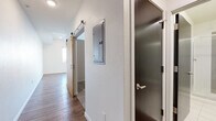Located at 820 N Sherman St in Denver's Capitol Hill neighborhood, this single-floor unit showcases a modern design aesthetic with consistent wood-look flooring throughout the main living areas. The open-concept layout connects the living space to the kitchen, creating a functional and cohesive floor plan.

The kitchen is well-appointed with white shaker-style cabinetry extending to the ceiling for generous storage, a subtle tile backsplash, dark stone countertops, and a full suite of stainless steel appliances including a refrigerator, electric range, microwave, and dishwasher. A window above the sink area allows natural light to brighten the workspace.

The main living area is clean and open, with recessed lighting, neutral white walls, and wood-look flooring that lends warmth to the space. A sliding barn door adds a contemporary architectural detail to the hallway, which also features an accessible electrical panel and an additional dark-toned interior door.

The bathroom is finished in crisp white tile, featuring a glass-enclosed walk-in shower with a built-in bench seat, chrome fixtures, and clean, minimal detailing. The overall ambiance of the unit is modern and move-in ready, with thoughtful finishes that balance practicality and style.