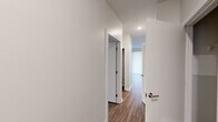 This single-floor, 2-bedroom, 2-bathroom unit offers a clean, modern design with consistent wood-look flooring and neutral gray walls throughout. The combined kitchen and living area serves as the heart of the home, anchored by a well-equipped kitchen featuring rich cherry wood cabinetry, granite-style countertops, stainless steel appliances — including a refrigerator, range, microwave, and dishwasher — and recessed lighting. A large vertical blind-covered sliding door in the kitchen/living area allows for ample natural light.

A central hallway connects the bedrooms and bathrooms, maintaining a logical and efficient layout. The spacious primary bedroom offers generous square footage with hardwood-style flooring and a dedicated closet with built-in shelving. The second bedroom also features wood-look flooring and a window with natural views, providing a bright and inviting atmosphere. Both rooms feature clean white walls and crisp white trim throughout.

The bathrooms are finished with neutral tile flooring, white tiled shower-tub surrounds, dark wood vanity cabinetry, and light countertops. Windows in the bathrooms provide natural light and ventilation. Three closets across the unit provide practical storage. Overall, the space presents a cohesive, move-in-ready aesthetic with a neutral palette and durable finishes.