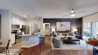 This single-story residence on Kingsclere Drive in Cary, NC offers a thoughtfully designed open-concept layout with consistent wood-style flooring throughout the main living areas. The kitchen is outfitted with white shaker cabinetry, granite countertops, a tile backsplash, and stainless steel appliances, including a refrigerator, range, microwave, and dishwasher. A breakfast bar provides additional seating and connects the kitchen seamlessly to the living and dining areas.

The living room is a standout space, featuring a wood-burning fireplace, a ceiling fan, a built-in display niche, and a sliding glass door that opens to a private patio with outdoor views. A bold accent wall adds visual depth to the space.

The bedroom features plush carpeting, multiple windows allowing generous natural light, and a dark accent wall that creates a cozy, intimate atmosphere. Two full bathrooms are present, each finished with granite-topped white vanities, large mirrors with built-in lighting, and wood-style flooring.

Additional conveniences include an in-unit washer with overhead shelving in a dedicated laundry space. The overall ambiance is modern and welcoming, balancing neutral tones with contemporary finishes throughout.