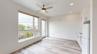 Located at 5460 N Interstate Ave in Portland, Oregon, this thoughtfully designed one-bedroom, one-bathroom unit offers a bright and efficient layout across a single floor. The open living area is the heart of the space, showcasing light-toned hardwood flooring, crisp white walls, and abundant natural light streaming through large windows. A brass-accented ceiling fan adds a modern yet warm touch overhead, complemented by recessed lighting. A glass balcony door opens to an outdoor space with views of the surrounding tree canopy and neighborhood rooftops, including a glimpse of a classic Portland water tower. The integrated kitchen lines one wall with sleek white cabinetry, open shelving, a stainless steel sink, and built-in appliances, maintaining a seamless and uncluttered aesthetic. The bedroom is a cozy, well-defined retreat featuring a built-in closet with wire shelving for organized storage and continued hardwood flooring. The bathroom is finished in a clean, contemporary style with a floating white vanity, white quartz countertop, an undermount sink with a chrome faucet, a frameless mirror, and a window that brings in natural light. The overall ambiance is modern, minimal, and move-in ready.