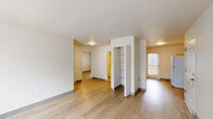 Located at 1921 Fir Rd in Forest Grove, Oregon, this single-story 2-bedroom, 1-bathroom unit offers a practical and well-organized layout. Light wood-tone flooring flows throughout the main living areas, creating a clean and cohesive look. The living room is bright and open, with vertical blinds filtering natural light and providing a neutral canvas for a variety of furnishing arrangements. An open-concept dining area connects seamlessly to the kitchen, which is outfitted with warm oak-toned cabinetry, ample upper and lower storage, gray laminate countertops, a double-basin sink, and white appliances including an electric range and refrigerator. A back door in the kitchen leads to the exterior, allowing additional natural light into the space. A dedicated pantry adds further storage convenience. Both bedrooms are comfortably sized with large windows dressed in vertical blinds, light flooring, and easy access to closets — three closets are distributed throughout the unit. The bathroom includes a full bathtub with shower, grab bars for accessibility, and neutral finishes. A utility room and additional unclassified space round out the functional floor plan, making this a well-appointed and practical home.
