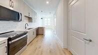 Located at 541 J Pl in Plano, TX, this efficiently designed single-floor unit offers a thoughtfully curated layout that maximizes every square foot. The open kitchen serves as a central highlight, featuring soft gray shaker-style cabinetry with sleek black hardware, a classic white subway tile backsplash, white quartz countertops, a black matte faucet, and stainless steel appliances including a range, microwave, dishwasher, and refrigerator. Pendant lighting and recessed fixtures illuminate the space, while light hardwood flooring flows seamlessly throughout, creating a bright and airy atmosphere. Natural light pours in through a large window at the far end of the main living area, enhancing the clean, open feel of the space. A ceiling fan adds both function and style to the living area. The bathroom is finished with warm hardwood-style flooring, a wall-length vanity with sage green cabinetry, black hardware, a white countertop, and a framed mirror. The walk-in closet, accessible directly from the bathroom, is carpeted and outfitted with built-in shelving units and double hanging rods on multiple walls, offering generous and organized storage. The overall aesthetic is modern and neutral, with a cohesive design palette throughout.