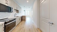 Located at 541 J Pl in Plano, TX, this efficiently designed single-floor unit offers a thoughtfully curated layout that maximizes every square foot. The open kitchen serves as a central highlight, featuring soft gray shaker-style cabinetry with sleek black hardware, a classic white subway tile backsplash, white quartz countertops, a black matte faucet, and stainless steel appliances including a range, microwave, dishwasher, and refrigerator. Pendant lighting and recessed fixtures illuminate the space, while light hardwood flooring flows seamlessly throughout, creating a bright and airy atmosphere. Natural light pours in through a large window at the far end of the main living area, enhancing the clean, open feel of the space. A ceiling fan adds both function and style to the living area. The bathroom is finished with warm hardwood-style flooring, a wall-length vanity with sage green cabinetry, black hardware, a white countertop, and a framed mirror. The walk-in closet, accessible directly from the bathroom, is carpeted and outfitted with built-in shelving units and double hanging rods on multiple walls, offering generous and organized storage. The overall aesthetic is modern and neutral, with a cohesive design palette throughout.
