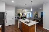 Located at 329 Broomsedge Trail in Chattanooga, Tennessee, this single-floor residence offers a thoughtfully designed open-concept layout with contemporary finishes throughout. The kitchen serves as a central hub, featuring striking two-tone cabinetry with warm wood lower cabinets and crisp white uppers, granite countertops, a large island with an undermount sink and bar seating, subway tile backsplash, and a full suite of stainless steel appliances. Pendant lighting overhead adds a refined touch. The kitchen flows seamlessly into the living area, which is anchored by rich hardwood flooring, a ceiling fan, and French doors that invite abundant natural light and provide direct access to an outdoor patio. The bedrooms are carpeted for comfort, each equipped with ceiling fans and windows that bring in natural light. The bathrooms are finished with granite vanity countertops, white cabinetry, and a tub-shower combination. A dedicated in-unit laundry area accommodates a full-size washer and dryer with additional shelving for storage. Throughout the home, neutral wall tones and clean architectural lines create a cohesive, modern ambiance well-suited for comfortable everyday living in the Chattanooga area.