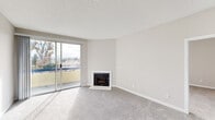 This single-floor residence offers a thoughtfully designed layout encompassing two bedrooms, two bathrooms, a combined living and dining area, a full kitchen, a closet, and a hallway. The living room serves as the centerpiece of the home, featuring a classic corner fireplace with a clean white surround and plush carpeting underfoot. Large sliding glass doors open directly onto a private balcony, bathing the space in natural light and offering open outdoor views of the surrounding landscape and distant scenery. The kitchen is well-equipped with rich dark cabinetry, crisp white countertops, light hardwood-style flooring, and stainless steel appliances including a gas range and microwave. Adjacent to the kitchen, the dining area features matching hardwood-style flooring, a pendant light fixture, and a window that brings in additional natural light. The primary bedroom is generously sized, carpeted, and includes a window with outdoor views. A dedicated walk-in closet with dual hanging rods and hardwood-style flooring provides ample storage. The bathrooms are finished in a clean, neutral palette, with one featuring a full tub and shower combination with brushed nickel fixtures. Neutral tones and textured ceilings carry throughout, creating a cohesive and inviting atmosphere.
