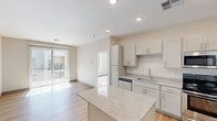 This thoughtfully designed 1-bedroom, 2-bathroom residence offers a efficient and functional single-floor layout with contemporary finishes throughout. The kitchen serves as a central highlight, featuring shaker-style cabinetry in a soft grey-white finish, granite countertops, a full suite of stainless steel appliances including a range, microwave, dishwasher, and refrigerator, and a central island with additional counter space. Warm-toned hardwood-style flooring flows through the kitchen and living areas, creating a cohesive and inviting atmosphere. The open layout connects the kitchen to the living space, which benefits from natural light and sliding door access to a balcony. The bedroom is carpeted for comfort, features a window with blinds that invite natural light, and offers a quiet, private retreat. Both bathrooms are finished with matching granite vanity tops, grey-toned cabinetry, and hardwood-style flooring, with one bathroom featuring a soaking tub and shower combination. Neutral wall tones and recessed lighting throughout lend the space a clean, modern aesthetic. An in-unit laundry area adds everyday convenience, rounding out this well-equipped residence.