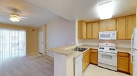 This single-story residence is thoughtfully designed with a functional, open layout that connects the kitchen and living areas seamlessly. The kitchen is well-equipped with warm honey-toned wood cabinetry offering generous storage, light-colored countertops, and a full suite of white appliances including a gas range, built-in microwave, dishwasher, and refrigerator. A peninsula counter extends into the living space, creating a natural divide while maintaining an open feel. The kitchen features easy-care tile flooring, while the adjacent living and dining areas transition to neutral wall-to-wall carpeting.

The living area is bright and comfortable, highlighted by a ceiling fan with light fixture and large sliding glass doors fitted with vertical blinds, allowing for natural light and outdoor access. The carpeted bedrooms each include ceiling fans and are finished with neutral tones, providing a calm and restful atmosphere. Doors connect the bedrooms to the rest of the home with ease.

A dedicated in-unit laundry area accommodates a full-sized washer and dryer side by side, with overhead shelving for added storage. The bathroom features tile flooring and a combined tub and shower enclosed by sliding glass doors with chrome hardware, offering both style and practicality throughout.