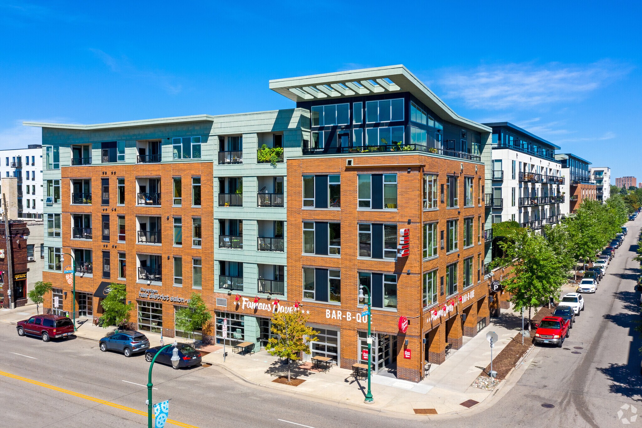 Exterior of a modern brick apartment building with balconies and large windows on a sunny day.