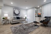 Located in the vibrant Los Feliz neighborhood of Los Angeles, this single-floor residence at 1840 N Kenmore Ave offers a well-designed layout with modern finishes and an abundance of natural light throughout. Light hardwood flooring flows seamlessly across the entire unit, creating a cohesive and inviting atmosphere.

The living room is a bright, comfortable space anchored by large sliding glass doors fitted with vertical blinds that frame lush greenery outside and open onto a balcony area. Recessed lighting and a mirrored accent wall add depth and warmth to the room. Adjacent to the living area, the dining space features a tray ceiling detail and connects directly to the kitchen via a pass-through bar counter.

The kitchen is thoughtfully appointed with white cabinetry, dark countertops, stainless steel appliances, and a striking mosaic tile backsplash. A window above the sink provides natural light and outdoor views, enhancing the functional yet stylish space.

The bedroom is generously proportioned, offering large windows with verdant tree views, recessed lighting, and ample room for a full furniture arrangement. A separate vanity area with a wide mirror and sliding glass doors adds a refined touch.

The bathroom features clean white cabinetry, dark countertops, a shower with curtain enclosure, and a large mirror that amplifies the sense of space. The overall design is contemporary, clean, and well-suited to modern urban living.