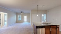 Located at 1001 Aventine Dr in Arden, NC, this well-appointed single-floor home offers three bedrooms, two bathrooms, and a thoughtfully designed layout. The open-concept kitchen and living area serves as the heart of the home, where rich dark-wood cabinetry, granite countertops, and a full suite of stainless steel appliances — including a refrigerator, range, and microwave — create a functional and stylish cooking space. A central island with a built-in sink and elegant pendant lighting adds both workspace and visual appeal, while track lighting illuminates the kitchen. The living room features plush carpeting, a ceiling fan, and natural light from multiple windows. Each bedroom is carpeted and equipped with a ceiling fan, with the primary bedroom offering generous closet space complete with wire shelving systems. The bathrooms are finished with dark wood vanities, and one features a soaking tub-shower combination with tile surround and wood-look flooring. Additional highlights include four closets, a dedicated laundry area, a hallway connecting the private quarters, and a patio for outdoor enjoyment. The warm, neutral color palette throughout lends the space a clean and inviting ambiance.
