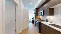 Located at 6606 Variel Ave in the Canoga Park neighborhood of Los Angeles, this modern single-floor studio is thoughtfully designed to maximize functionality and style. The open-concept layout seamlessly connects the living, sleeping, and kitchen areas, creating a bright and cohesive living environment illuminated by recessed lighting throughout.

The galley-style kitchen is a standout feature, finished with rich dark wood cabinetry, crisp white quartz countertops, and a geometric white tile backsplash. A full suite of stainless steel appliances — including a gas range, microwave, refrigerator, and dishwasher — makes this kitchen both practical and visually striking. Light wood flooring extends throughout the entire space, lending warmth and continuity.

The living area offers an open and airy feel with clean white walls that serve as a versatile backdrop. A four-poster bed frame anchors the sleeping zone, which features a bold teal accent wall that adds a vibrant design element. The bathroom is finished with large-format light gray tile flooring, a dark wood vanity, an LED-backlit mirror, and built-in shelving for storage.

Louvered interior doors and modern hardware throughout add architectural character, while recessed lighting ensures a well-lit, contemporary ambiance across the entire space.