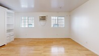 Located at 403 S Alvarado St in the heart of Los Angeles, this single-story, one-bedroom, one-bathroom unit offers an efficient and well-organized layout. The spacious main room serves as the primary bedroom, featuring gleaming light hardwood floors, bright white walls, and multiple windows fitted with blinds that invite natural light while maintaining privacy. A wall-mounted air conditioning unit ensures year-round comfort. A built-in white cabinetry unit with shelving and drawers lines one wall, providing generous storage without sacrificing floor space. The kitchen is thoughtfully designed with crisp white shaker-style cabinetry, dark granite countertops, a stainless steel gas range, a refrigerator, and an under-cabinet range hood. The tile flooring and ample counter space make it both functional and visually clean. A dedicated closet offers additional organized storage. The bathroom features full tile surround walls, a soaking tub with overhead shower, a toilet, and a vanity, all finished in a neutral, classic palette. The unit's clean, minimal aesthetic throughout creates a bright and functional living environment well-suited to urban Los Angeles living.