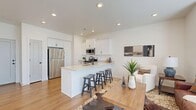 Located at 1848 W 700 S in Lehi, Utah, this two-story home offers a thoughtfully designed layout across two floors. The main level hosts an open-concept living, dining, and kitchen area, creating a welcoming and connected space. The kitchen is outfitted with white shaker-style cabinetry, stainless steel appliances including a gas range, built-in microwave, and refrigerator, all centered around a peninsula with bar seating — ideal for casual dining and entertaining. Warm hardwood-style flooring flows throughout the main level, complemented by recessed lighting and a bright, neutral color palette. The living area features natural light from front-facing windows and a modern entry door with glass panels. A half bathroom is conveniently located on the main floor, alongside a dedicated laundry room equipped with hookups and utility connections. Upstairs, the primary bedroom is generously sized with plush carpeting, dual windows that fill the room with natural light, and direct access to a closet. The primary bathroom features a dual-sink vanity with white cabinetry, matte black hardware, and light tile flooring. A second bedroom and additional bathroom complete the upper level, offering comfortable accommodations for residents or guests. Three closets throughout provide ample storage.