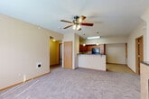Located at 1016 Haeffele Way in Bloomington, Illinois, this single-floor, three-bedroom, two-bathroom home offers a practical and comfortable layout. The open-concept living area is carpeted and features a ceiling fan and a tiled fireplace, creating a warm focal point in the room. A window allows natural light to brighten the space. The kitchen is seamlessly integrated into the living area via a peninsula counter, offering dark countertops, warm wood cabinetry, pendant lighting, and black appliances, including a refrigerator. Tile flooring flows through the kitchen and into adjoining utility areas. The three bedrooms are well-proportioned, with the spacious primary bedroom offering generous room to furnish comfortably. Each bedroom features plush carpet, ceiling fans, and access to one of the five closets distributed throughout the home. The two bathrooms include tile flooring and tub-shower combinations. A dedicated laundry room houses a full-size washer and dryer with overhead shelving for storage. A utility room and hallway round out the floor plan, which is designed for efficient single-level living. Neutral tones and warm wood accents throughout lend a cohesive, understated aesthetic to this well-appointed Bloomington home.