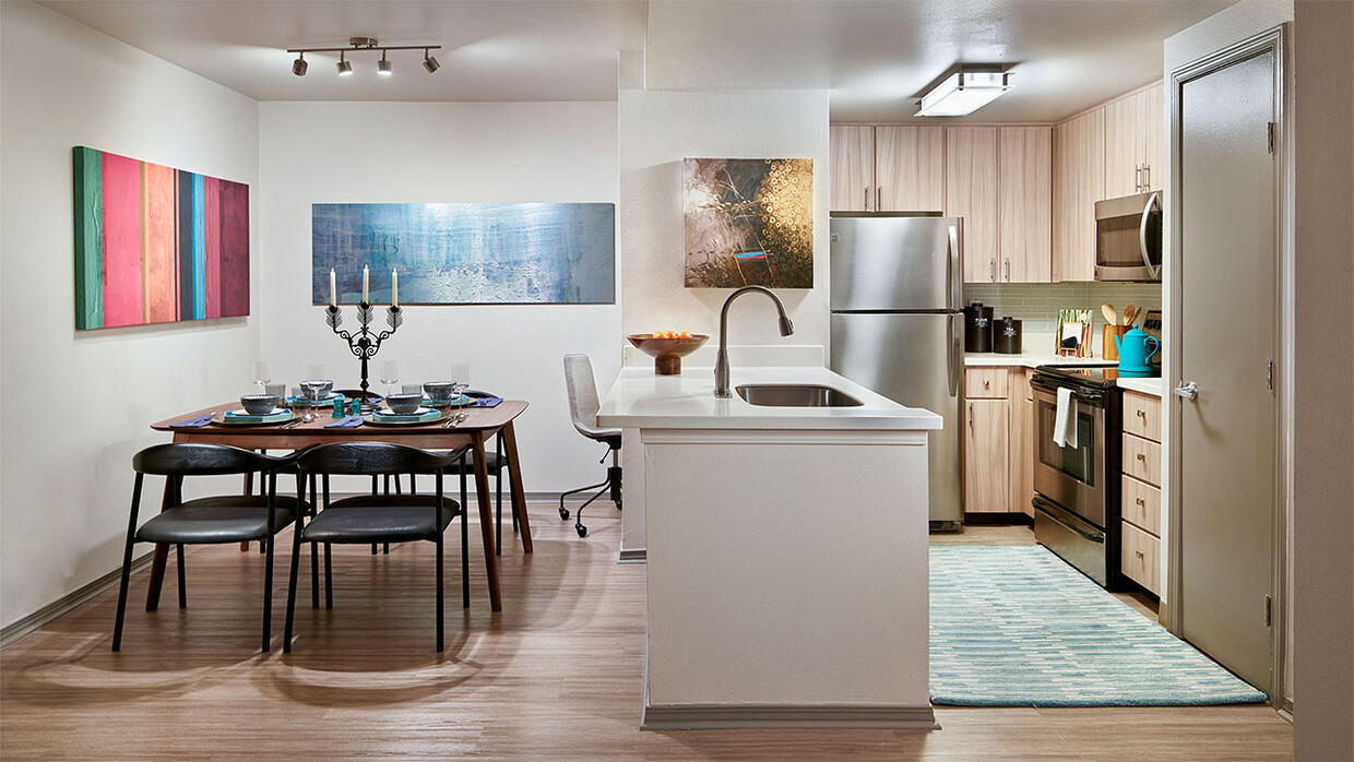 Cocina del apartamento con electrodomésticos de acero inoxidable, comedor y piso de madera. - Griffis North Creek