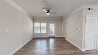 Located on Ronald Reagan Pkwy in Lawrenceville, GA, this well-appointed 2-bedroom, 2-bathroom single-floor home offers a thoughtfully designed layout with quality finishes throughout. The living room serves as a welcoming centerpiece, featuring rich hardwood-style flooring, crown molding, a ceiling fan, and large windows alongside a glass door that invite abundant natural light and views of the surrounding greenery. The kitchen is a functional highlight, showcasing granite countertops, white shaker-style cabinetry, a tile backsplash, and a full suite of stainless steel appliances, including a refrigerator, range, and microwave. A breakfast bar provides additional prep and dining space. A connecting hallway leads to both bedrooms, each finished with plush carpeting and ceiling fans. The spacious primary bedroom includes a walk-in closet equipped with wire shelving for organized storage. The second bedroom features a window with outdoor views and access to a dedicated closet. Both bathrooms are finished with granite-topped vanities, white cabinetry, wood-style flooring, and tub-shower combinations. Crown molding and a textured ceiling add architectural character, while the neutral color palette creates a clean, cohesive ambiance throughout the home.