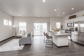 This thoughtfully designed three-story home offers a bright, contemporary interior defined by clean lines and a neutral color palette throughout. The main living level centers on an open-concept layout that seamlessly connects the living room, dining area, and kitchen. Large sliding glass doors lead to a private balcony, flooding the space with natural light and offering views of the surrounding neighborhood. Dark hardwood-style flooring anchors the main level, complementing the crisp white walls and recessed lighting overhead.

The kitchen is well-equipped with white shaker cabinetry, granite-look countertops, stainless steel appliances—including a gas range, microwave, and refrigerator—and a central island with bar seating, making it ideal for both cooking and casual dining.

Bedrooms are finished with plush carpeting, ceiling fans, and ample natural light from well-positioned windows. The primary bedroom features an en-suite bathroom and a walk-in closet, while additional bathrooms include white vanities with large mirrors and hardwood-style flooring. A dedicated in-unit laundry area with a full-size washer and dryer adds everyday convenience. A staircase connects all three levels, reinforcing the home's functional and cohesive design.
