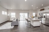 This thoughtfully designed three-story home offers a bright, contemporary interior defined by clean lines and a neutral color palette throughout. The main living level centers on an open-concept layout that seamlessly connects the living room, dining area, and kitchen. Large sliding glass doors lead to a private balcony, flooding the space with natural light and offering views of the surrounding neighborhood. Dark hardwood-style flooring anchors the main level, complementing the crisp white walls and recessed lighting overhead.

The kitchen is well-equipped with white shaker cabinetry, granite-look countertops, stainless steel appliances—including a gas range, microwave, and refrigerator—and a central island with bar seating, making it ideal for both cooking and casual dining.

Bedrooms are finished with plush carpeting, ceiling fans, and ample natural light from well-positioned windows. The primary bedroom features an en-suite bathroom and a walk-in closet, while additional bathrooms include white vanities with large mirrors and hardwood-style flooring. A dedicated in-unit laundry area with a full-size washer and dryer adds everyday convenience. A staircase connects all three levels, reinforcing the home's functional and cohesive design.