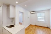 Located on the second floor at 3495 Avenue Van Horne in Montréal's Côte-des-Neiges neighbourhood, this one-bedroom, one-bathroom unit offers a thoughtfully efficient layout across a single floor. Warm honey-toned hardwood flooring runs throughout the main living areas, complementing the crisp white walls and recessed lighting that keep the space feeling bright and clean.

The open-concept living and kitchen area forms the heart of the unit. The kitchen is outfitted with white cabinetry, a white quartz countertop with an integrated sink, and built-in appliances including a microwave and an in-unit washer, maximizing functionality within a compact footprint. A window in the living area allows natural light to filter in, adding to the airy atmosphere.

The bedroom is a cozy, well-proportioned room featuring its own window with views of the surrounding neighbourhood, a recessed ceiling light, and a built-in sliding-door closet for ample storage.

The bathroom is finished in a modern style, with large-format grey tiles, a wall-mounted white vanity, a full-width mirror with shelving, and a glass-enclosed shower, creating a clean and polished aesthetic throughout. A hallway connects the rooms, completing this smartly designed urban residence.