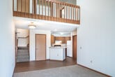Located at 851 O'Keeffe Ave in Sun Prairie, Wisconsin, this two-story, one-bedroom, two-bathroom home offers a well-designed layout spread across two equally sized floors. The main level features a kitchen equipped with warm oak cabinetry, ample counter space, a double sink, and white appliances including a range and refrigerator, all complemented by light hardwood-style flooring. The open living area on the upper level is a standout, boasting dramatic vaulted ceilings, a ceiling fan, and a sliding glass door that fills the space with natural light and leads out to a private balcony overlooking a lush, well-maintained green landscape. The bedroom is a comfortable, carpeted retreat with two windows that invite in natural light, while two closets provide ample storage. Both bathrooms are clean and functional, each featuring a full tub-shower combination with chrome fixtures and hardwood-style flooring with warm wood vanity cabinetry. A dedicated staircase connects the two floors. Baseboard heating is present throughout, ensuring year-round comfort. The outdoor balcony view showcases mature trees and manicured grounds, adding a peaceful, suburban charm to this Sun Prairie residence.
