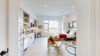 Located in Revere, MA, this well-appointed studio presents a smart, open-concept layout that maximizes every square foot across a single floor. Light wood-tone flooring runs throughout, contributing to a bright, cohesive aesthetic complemented by crisp white walls and recessed lighting.

The kitchen is a standout feature, outfitted with sleek light gray cabinetry, open shelving, and a subway tile backsplash. Stainless steel appliances — including a full-size refrigerator, dishwasher, electric range, and over-the-range microwave — provide full functionality. A built-in countertop workspace with additional seating seamlessly transitions the kitchen into a dining and work area.

The main living and sleeping area is generously proportioned for a studio, offering ample room for a full bedroom setup alongside a comfortable living arrangement. Recessed ceiling lighting and a large window allow natural light to fill the space, enhancing its open and airy atmosphere.

The bathroom is clean and modern, featuring large-format light tile flooring, a glass-enclosed walk-in shower with white tile surround, and matte black fixtures that add a contemporary accent. The overall design of this studio reflects modern urban living with purposeful, efficient use of space.