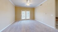 This single-floor, two-bedroom, two-bathroom residence at 4000 Walden Way in Flowery Branch, Georgia offers a practical and comfortable layout with a welcoming neutral palette throughout. The open-concept kitchen and living area serves as the heart of the home, featuring a peninsula with granite-look countertops, ample warm-toned wood cabinetry, black appliances including a range, microwave, and refrigerator, and hardwood-style flooring that adds warmth to the space. Crown molding accents the living area, lending a polished architectural detail to the open layout. The primary bedroom is a generously sized retreat, finished with plush carpeting, a ceiling fan, and French doors that invite natural light and provide outdoor access. The second bedroom also features carpet and a ceiling fan, with a wide window that brightens the room naturally. Both bathrooms are appointed with hardwood-style flooring, warm wood vanity cabinetry, and tub-shower combinations with tiled surrounds. A dedicated laundry room with wire shelving overhead, hardwood-style flooring, and washer/dryer hookups adds everyday convenience. Throughout the home, soft neutral tones, clean white trim, and consistent finishes create a cohesive and functional living environment.