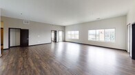 This single-floor unit presents a thoughtfully designed open-concept layout with a generous living area finished in rich, dark hardwood flooring throughout. The expansive main living space is bright and airy, benefiting from multiple large windows that frame urban skyline views, flooding the interior with natural light.

The kitchen is well-equipped and contemporary, featuring dark espresso cabinetry extending to the ceiling for ample storage, stainless steel appliances including a refrigerator, range, and built-in microwave, complemented by a subway tile backsplash and granite countertops. A central island with matching granite provides additional workspace and casual dining options, while a pendant light adds focused illumination overhead.

The bedroom is carpeted for comfort and includes a window with urban views. The unit features two bathrooms: one with a granite-topped vanity, dark cabinetry, and a walk-in shower with built-in shelving, and a second with a soaking tub/shower combination and matching vanity finishes. Large-format tile floors run throughout both bathrooms. In-unit laundry is also present, adding everyday convenience to this polished, modern space.