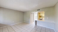 This classic 1-bedroom, 1-bathroom unit in Orlando, FL offers a straightforward, single-floor layout designed for comfortable everyday living. The living room features light-toned large-format tile flooring, neutral gray walls, and a textured ceiling, creating a bright and clean atmosphere. A wide window allows natural light to fill the space, with views of surrounding greenery adding a touch of the outdoors. The layout flows naturally from the living area toward the bedroom. The bedroom is carpeted for warmth and comfort, with neutral wall tones and a sliding glass door that opens to a private balcony overlooking lush outdoor scenery. The room includes access to a dedicated closet, providing practical storage. Connected to the bedroom is a full bathroom featuring tile flooring, a vanity with a speckled white countertop, white cabinetry, and a large mirror with overhead lighting. The overall design of the unit is clean and functional, with consistent neutral tones throughout that create a cohesive and versatile living environment. The combination of tile in the common areas and carpet in the bedroom adds both practicality and comfort to this well-organized classic floor plan.