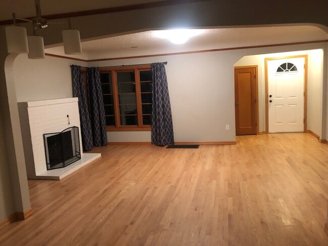 Large living room with hardwood floors and decorative (non-functioning) fireplace. - 4842 NE Mallory Ave